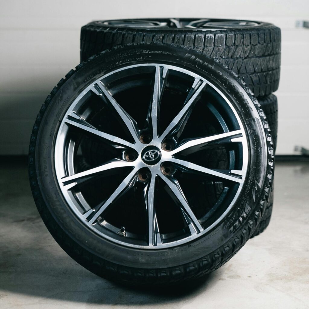 Close-up of stacked car tires and alloy wheels in a garage setting, showcasing automotive equipment.